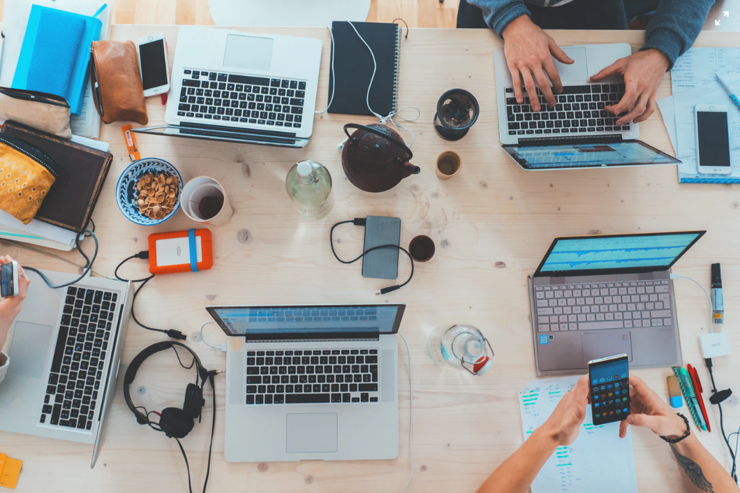 5 laptops with people working at them as seen from above